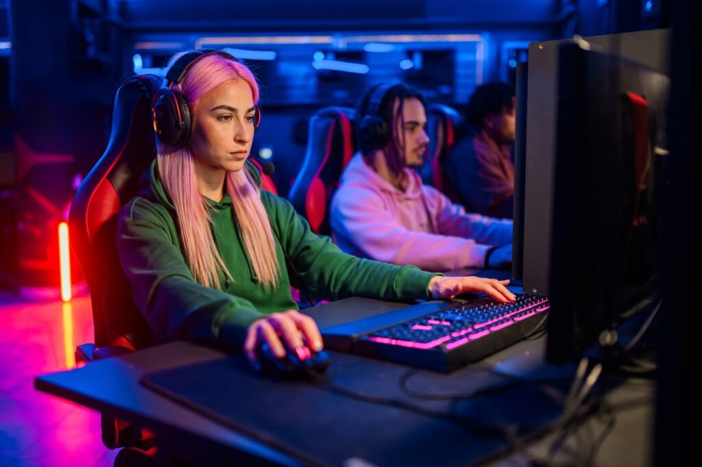 Young woman with pink hair gamer playing PC video game in a gameroom